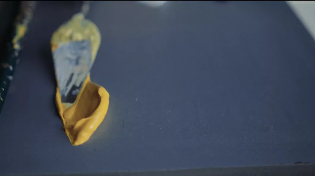 Tinta acrílica amarela recém-espalhada com a espátula sobre a paleta