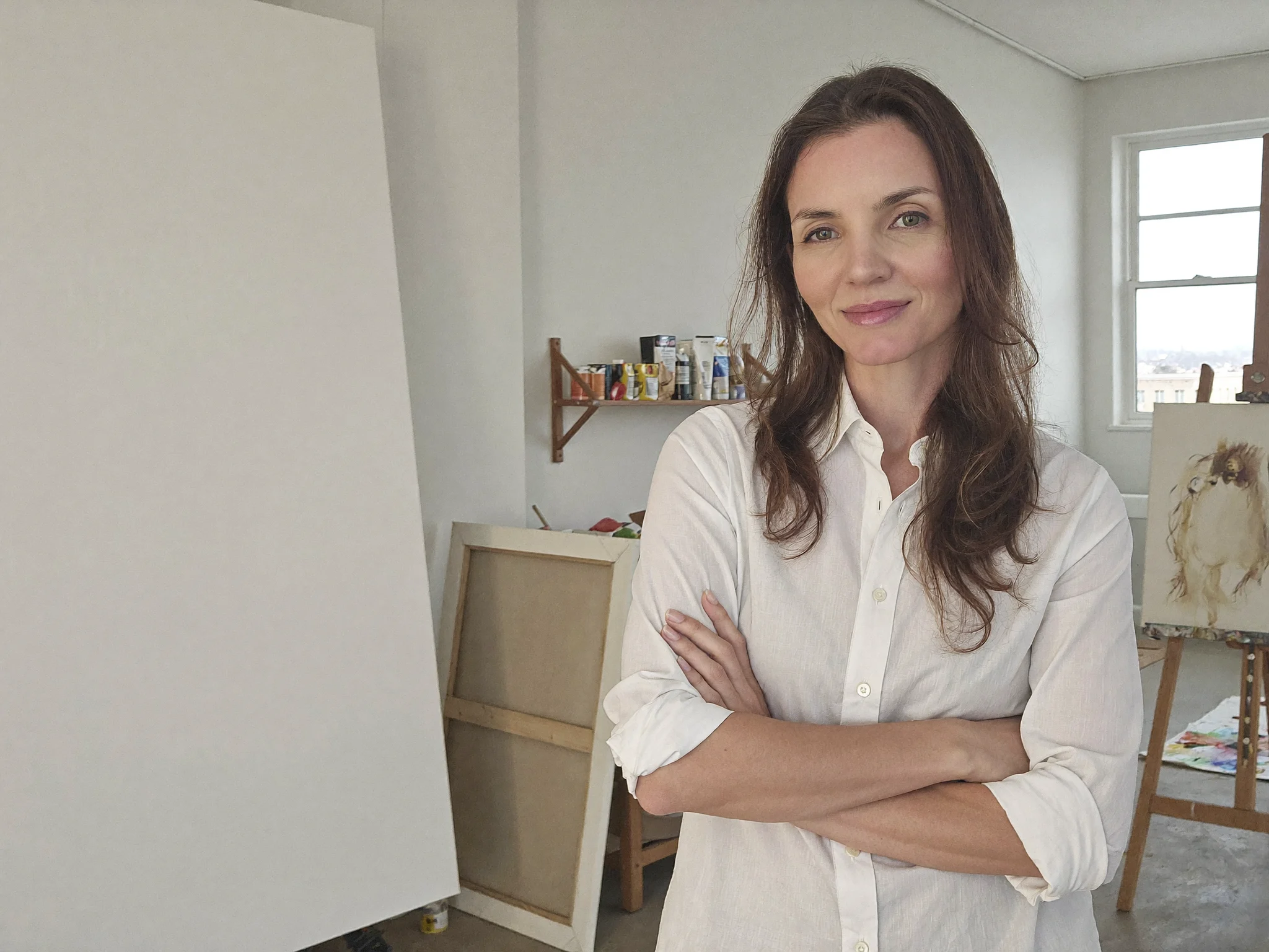 Lari Namaste de braços cruzados em seu ateliê iluminado