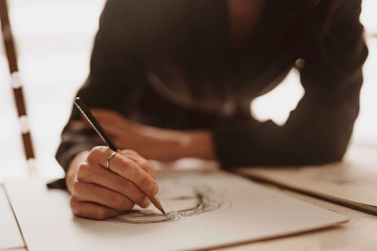 Mãos desenhando à caneta em um caderno sobre a mesa