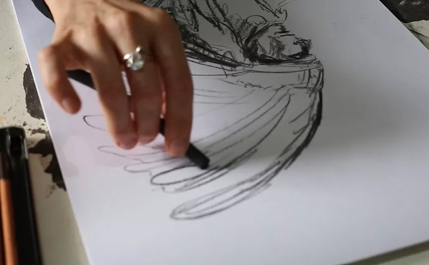 Mão traçando um esboço a lápis sobre o papel