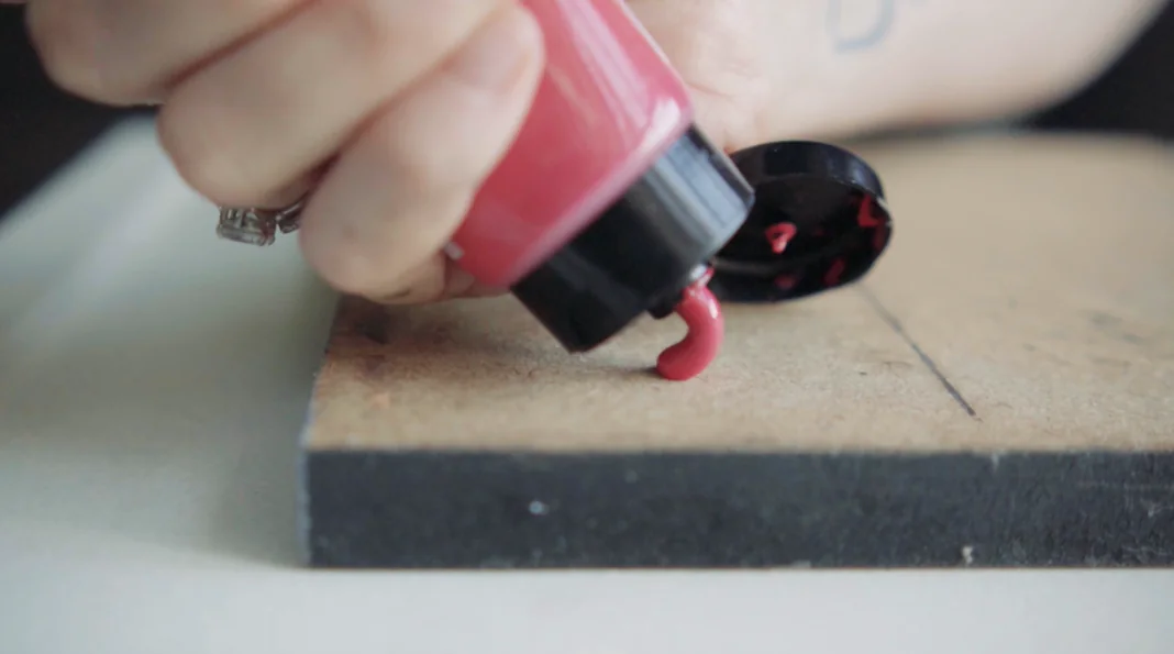 Tinta magenta sendo espremida do tubo sobre a paleta