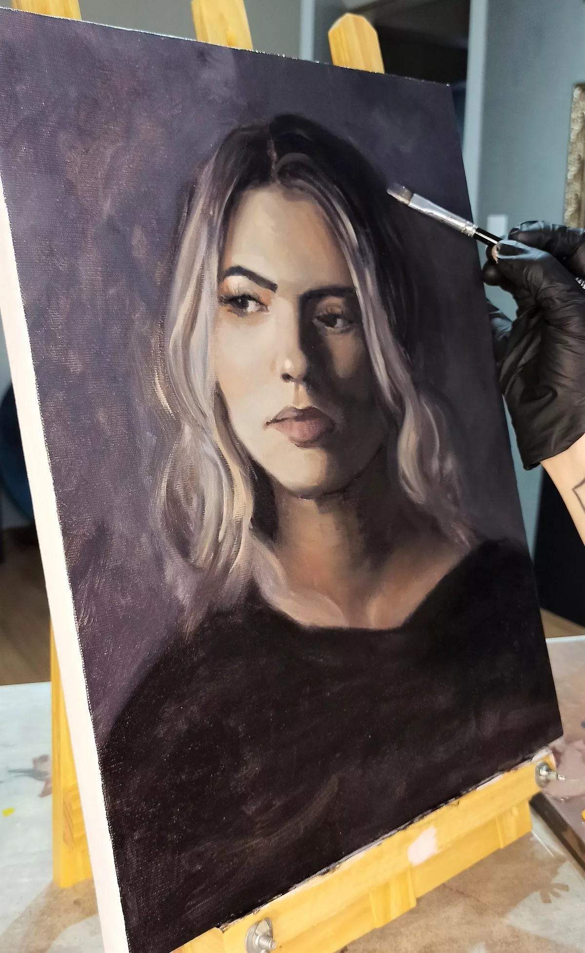 Retrato feminino pintado a óleo, em fase final sobre o cavalete, sendo acabado com pincel fino